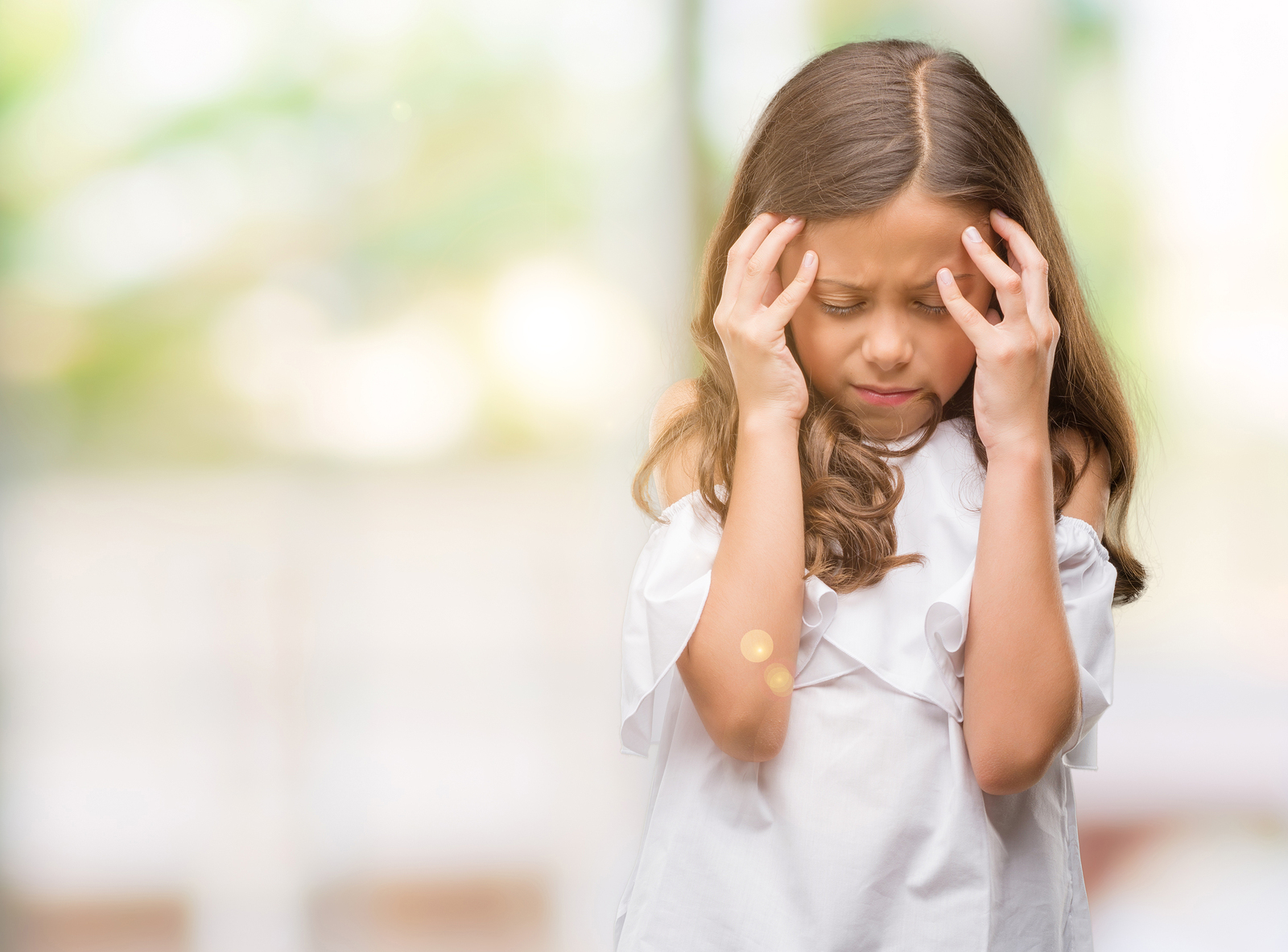 Brunette hispanic girl with hand on head for pain in head becaus